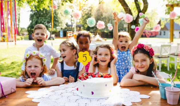 Image où il y a sept enfants qui fêtent l'anniversaire d'une petite fille qui a cinq ans.