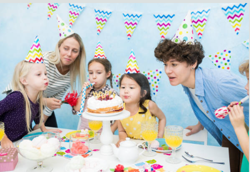 Image de trois enfants qui soufflent des bougies avec deux animateurs qui encadrent l'anniversaire.